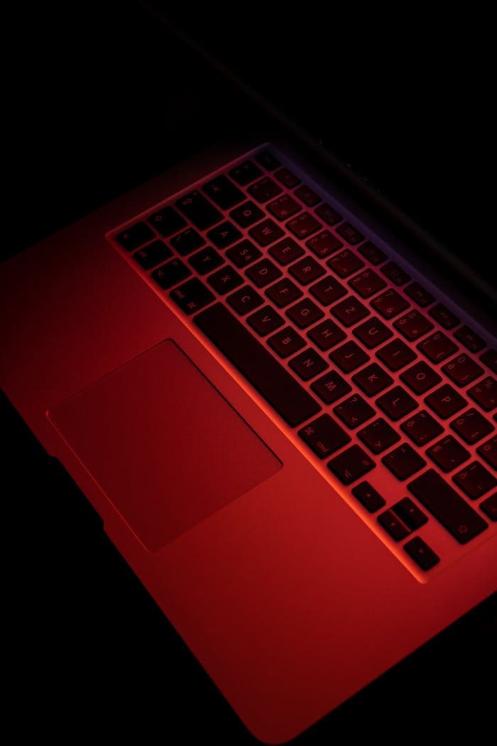 Close-up of a laptop keyboard under red lighting, emphasizing modern technology.